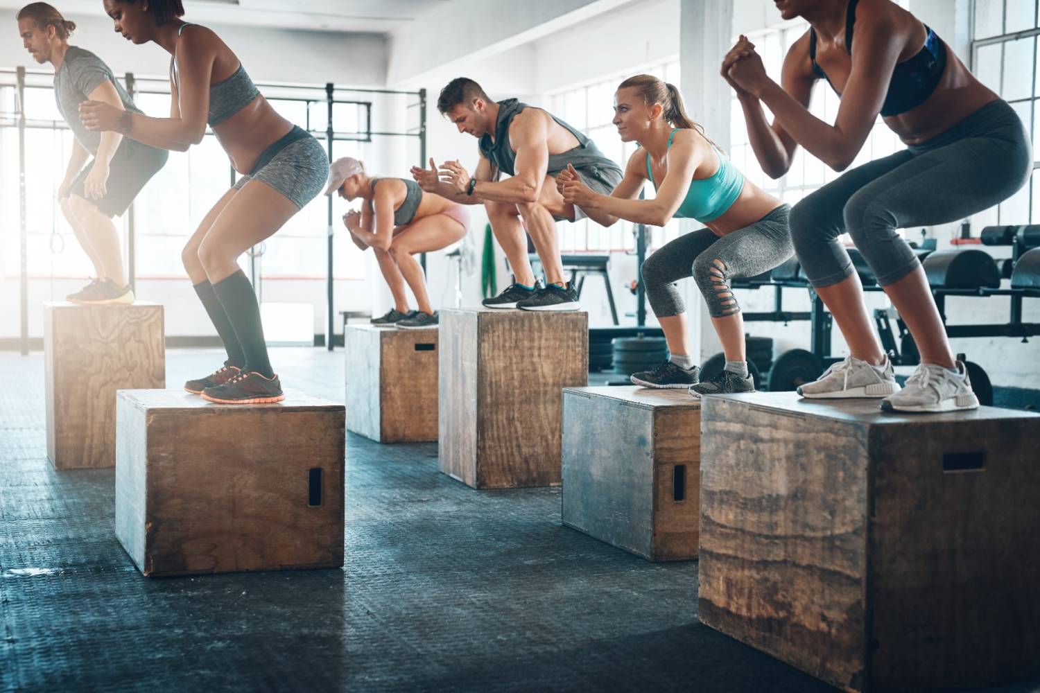 A gym class doing box jump squats