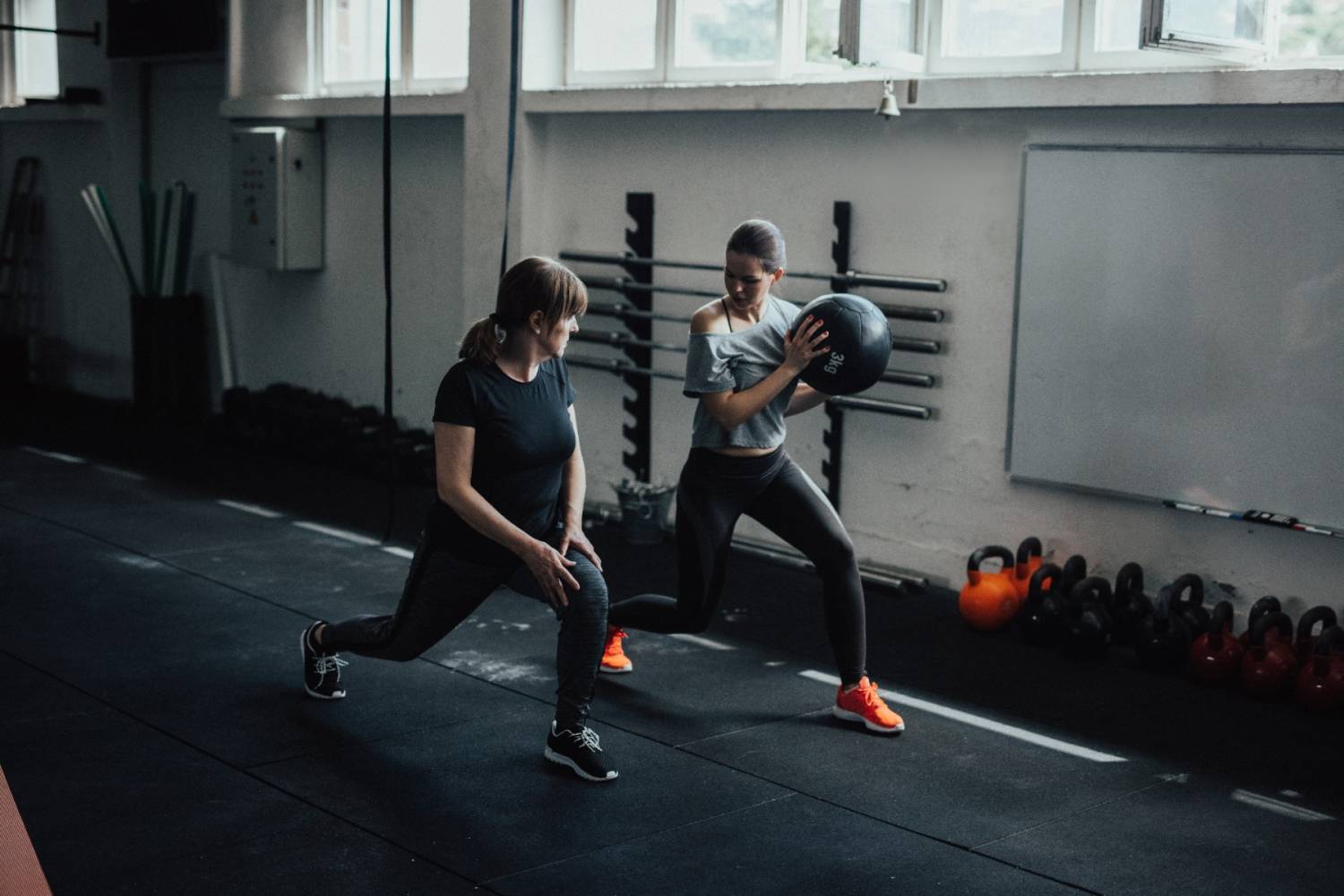 Two women training using medicine balls in an indoor gym