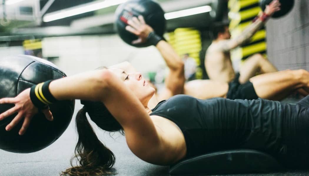 A woman lying down with a medicine ball behind her head